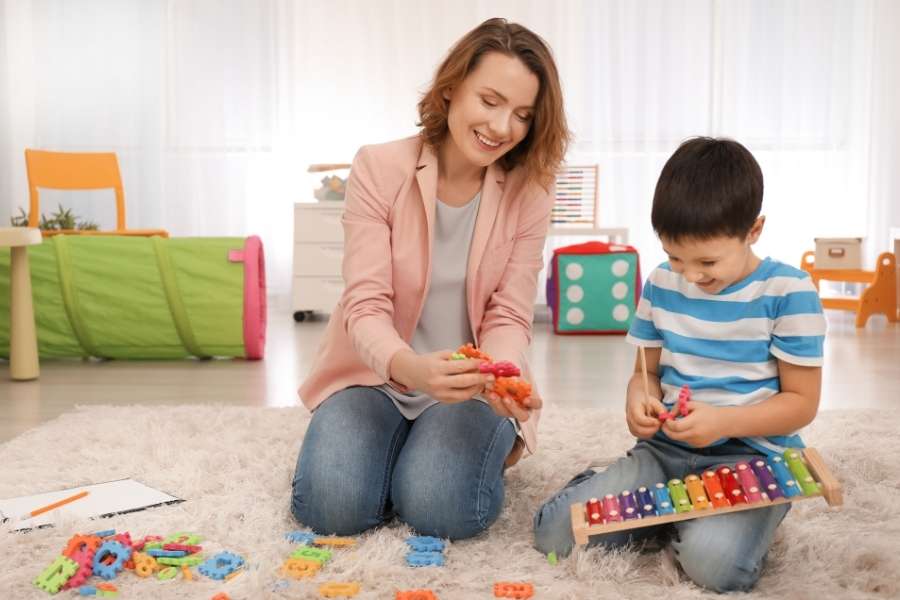Mãe interagindo com o filho em climaharmonioso em um espaço agradável e com brinquedos que a criança gosta.
