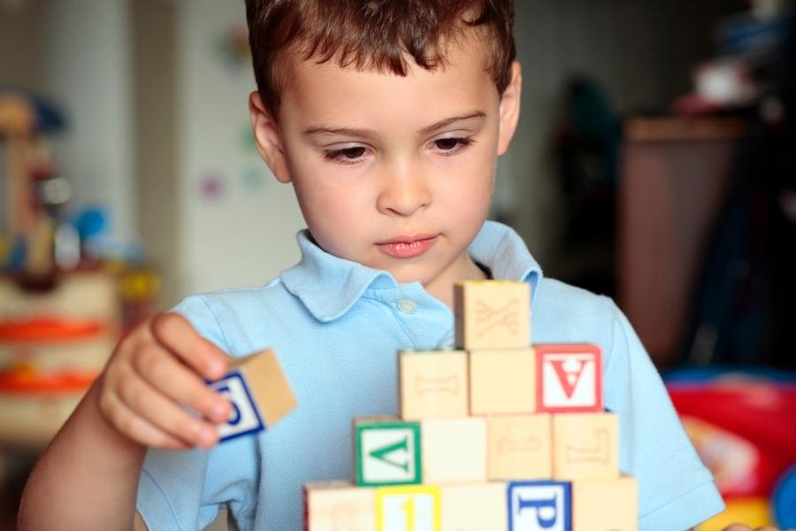 Menino autista brincando sozinho com blocos de montar